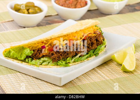 Beef Tacos - Mexican shredded beef tacos in soft corn tortillas served with lettuce, sour cream, grated cheddar cheese and salsa Stock Photo