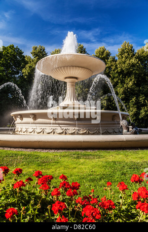 Red geraniums in front of the fountain in Ogród Saski, Saxon Garden, the oldest public park in Warsaw, Poland. Stock Photo