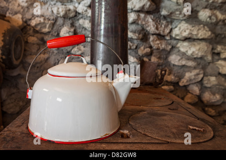 Antique metal tea kettle on top of wood burning stove Stock Photo