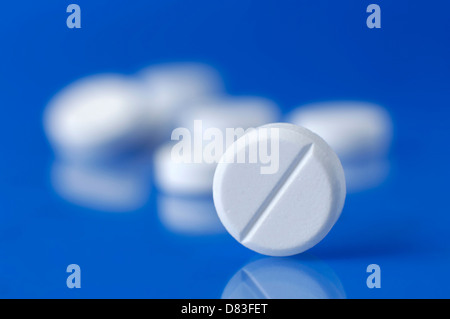 White tablets Medication pills isolated on blue background Stock Photo
