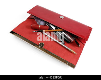 Open red womens handbag full of makeup and accessories closeup Isolated on white background Stock Photo