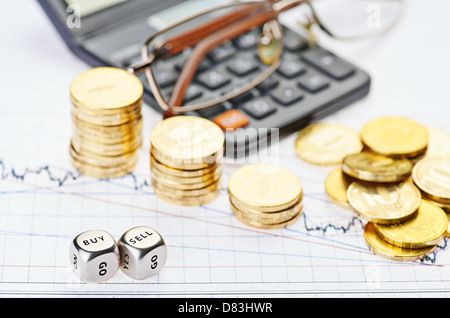 Downtrend stacks coins, calculator, glasses and dices cubes with the words SELL BUY on the financial stock charts. Stock Photo