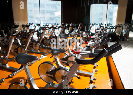 Aerobics spinning exercise bikes gym room with many in a row Stock Photo