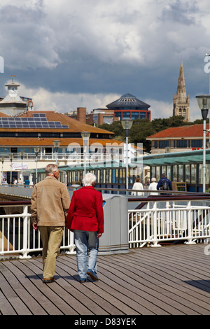 Elderly couple walking along Bournemouth Pier in May Stock Photo