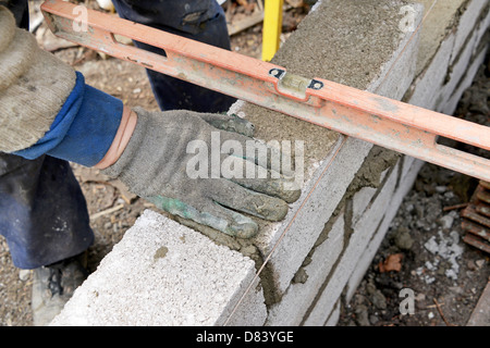 a builder checking level of a wall he is building Stock Photo