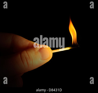 Hand holding burning match stick. Black isolated Stock Photo