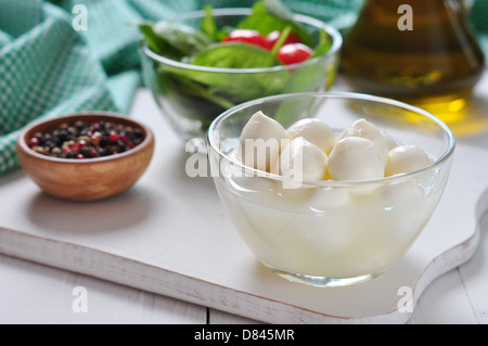 Mozzarella, tomatoes, basil and olive oil on white wooden background Stock Photo