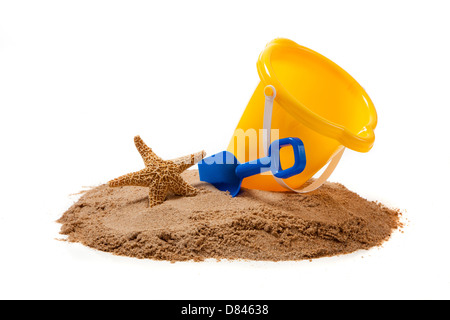 A yellow pail, blue shovel and a starfish on sand on a white background with copy space Stock Photo