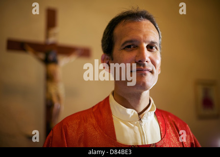 Man and faith, portrait of catholic priest on altar in church looking at camera and smiling Stock Photo