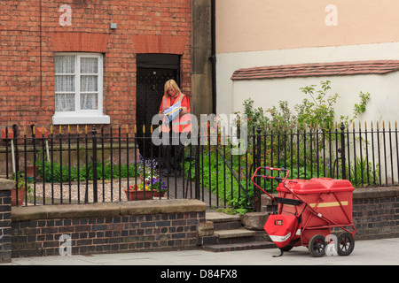 A female Royal Mail postal worker delivering post to a house on her round in Newport, Shropshire, England, UK, Britain Stock Photo