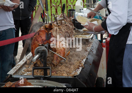 Cooking fast food at Ormskirk, Lancashire, UK 19th May, 2013. Serving, Spit Roast or Hog Roast at catering event. UK. A hog roast being prepared for carving and serving at Ormskirk's first Medieval Day where 12th-century re-enactment group Historia Normannis take people back in time. Stock Photo