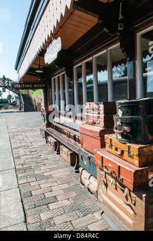 Old leather suitcases and trunks piled up on a platform by an old-fashioned waiting room at Severn Valley Steam Railway Stock Photo