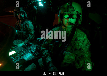 Pilots equipped with night vision goggles in the cockpit of a UH-60 Black Hawk Stock Photo