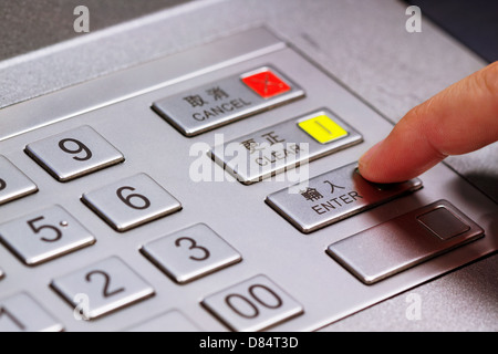 Hand entering personal identification number on ATM dial panel Stock Photo
