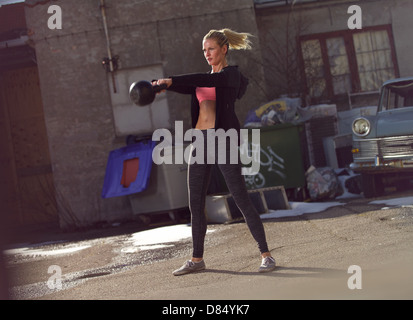 Young fitness woman swinging the kettlebell during crossfit training Stock Photo