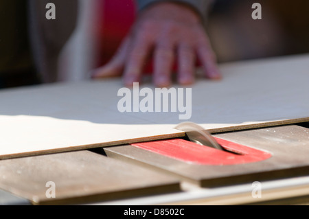 Senior man cutting plywood on a table saw. Stock Photo