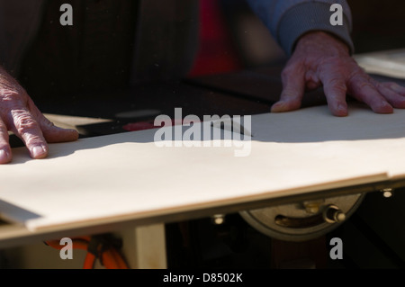Senior man cutting plywood on a table saw. Stock Photo