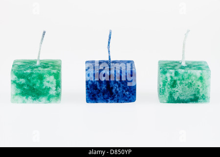 Three blue and green square candles isolated on a white background. Stock Photo