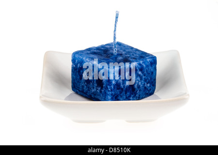 Candle on a plate isolated on a white background. Stock Photo