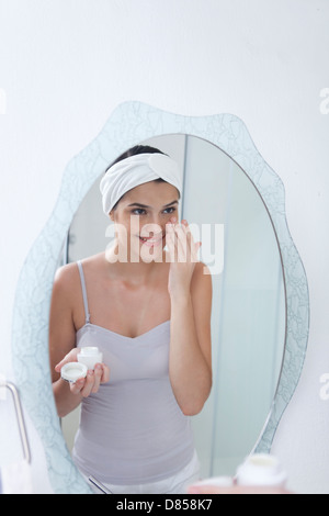 young woman applying face cream. Stock Photo