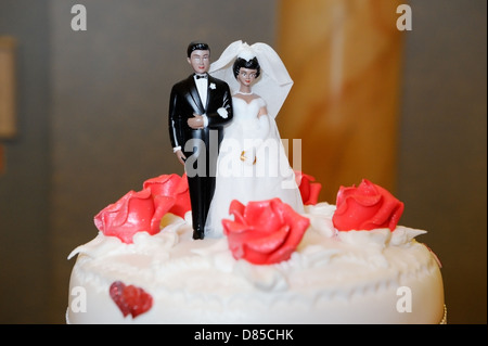 Ethnic Bride and groom decorate wedding cake Stock Photo
