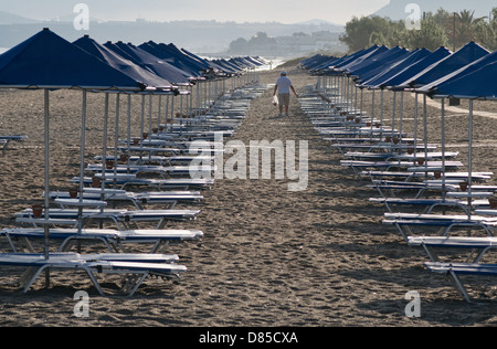 Empty beach sunbeds with solitary male figure in the distance Rethymna Beach Crete Stock Photo