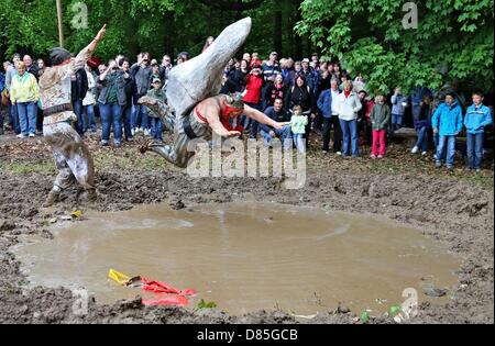 Hergisdorf, Germany. 20th May 2013. A participant jumps into a puddle of mud during the so-called 'Dirty Pig Festival' in Hergisdorf, Germany, 20 May 2013. The people of Hergisdorf use the annual event to banish the winter season. The puddle jumpers play the winter, participants dressed in white act as the summer. The participants in white use whips to force the puddle jumpers away, so that summer wins over winter. Photo: Jan Woitas/dpa/Alamy Live News Stock Photo