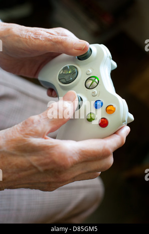 An elderly woman using Xbox 360 gamepad Stock Photo