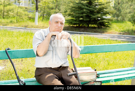 Portrait of senior man sitting on the bench park waiting for someone Stock Photo