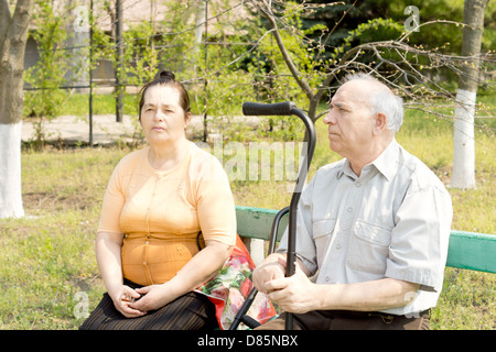 An old man and young woman sitting on the bench park Stock Photo