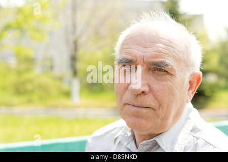 Close up portrait of senior bald man looking at something in the park Stock Photo
