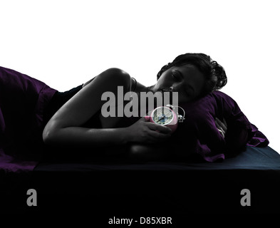 one woman sleeping hugging in bed alarm clock silhouette studio on white background Stock Photo