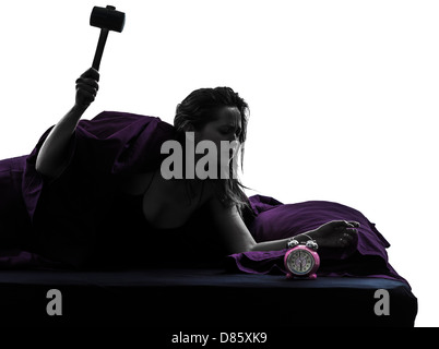 one woman in bed waking up smashing alarm clock silhouette studio on white background Stock Photo