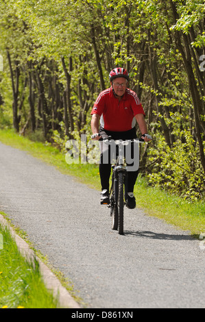 Mature gentleman cycling on the foot and cycle path adjacent to the Forth and Clyde canal in Glasgow, Scotland, UK Stock Photo