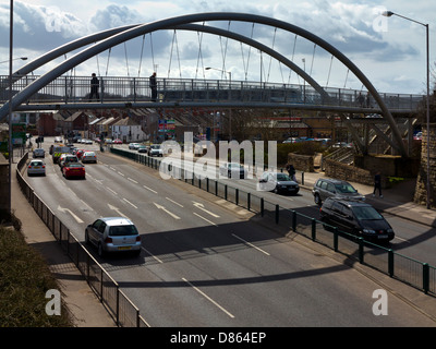 Curved pedestrian bridge over a busy main road in Mansfield town centre Nottinghamshire England UK with traffic on road below Stock Photo