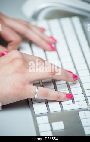 Close up shot of hands on a computer. A girl controls a mouse and keyboard whilst on the computer. Stock Photo