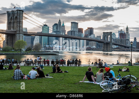 Families friends picnic on East River near Brooklyn Bridge in DUMBO neighborhood NYC Stock Photo
