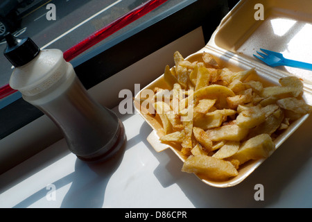 A polysyrene tray of french fries and bottle of vinegar in a fish & chip shop Llandeilo, Carmarthenshire Wales UK Stock Photo
