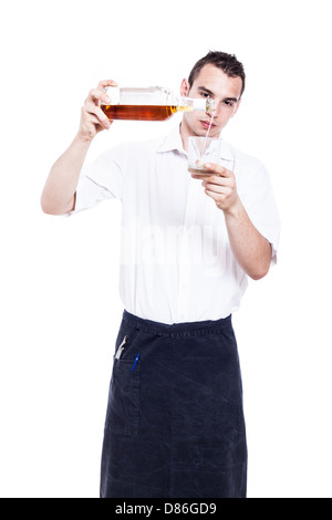 Young waiter pouring glass of whiskey, isolated on white background Stock Photo