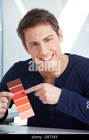 Smiling graphic designer with red color samples in his office Stock Photo