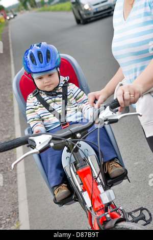 little boy with blue helmet on bicycle with mother Stock Photo