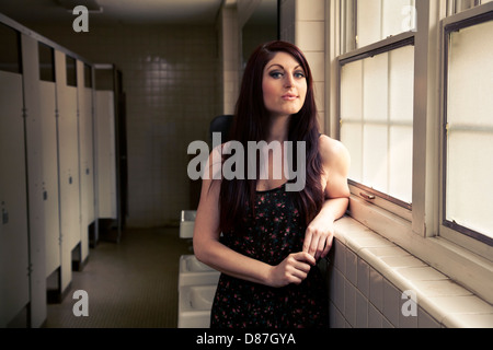 Woman standing next to window in public bathroom Stock Photo