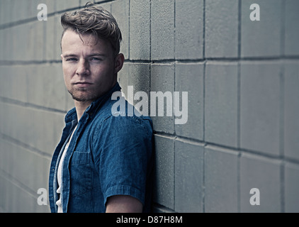 Man standing against block wall Stock Photo