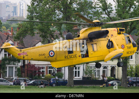 London, UK. 21st May 2013. A Royal Air Force Sea King Westland helicopter takes-off after a medical mission to deliver a patient to Kings College Hospital in Camberwell. As locals look on at the aircraft as it lifts off from Ruskin Park, Lambeth in south London, the yellow RAF search and rescue aircraft (SAR) leaves to return to base. Both RAF, Royal Navy and London air ambulances regularly use this public space for emergency transporting of casualties to the NHS Trust A&E department. Picture by Richard Baker / Alamy Live News. Stock Photo