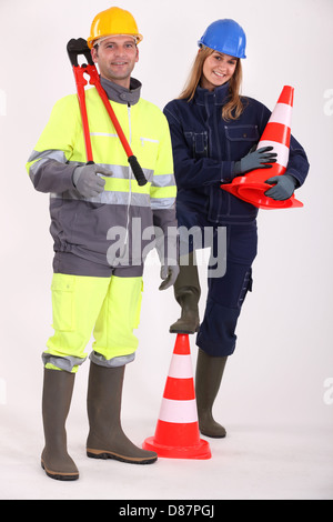 male and female bricklayers posing with construction cones Stock Photo