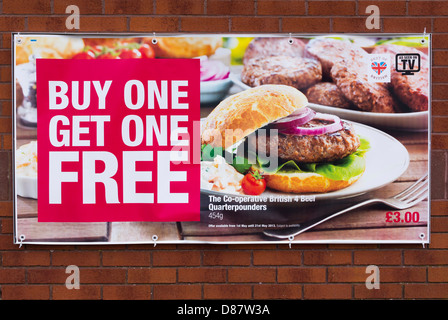 Buy one get one free food deal for cheap burgers on a poster on a co-op supermarket store front, UK Stock Photo