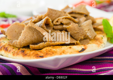 Donner Meat on Naan - Slices of donner meat on top of a flatbread served with salad, chilli and yoghurt. Stock Photo