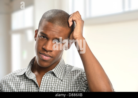 Portrait of young African American man scratching head indoors Stock Photo