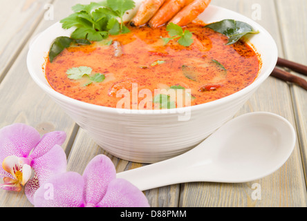 Tom Yum Nam Khon - Creamy Thai soup with prawns and mushrooms garnished with coriander and served with lime wedges. Stock Photo