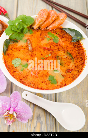 Tom Yum Nam Khon - Creamy Thai soup with prawns and mushrooms garnished with coriander and served with lime wedges. Stock Photo